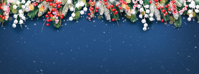 christmas banner with fir branches and white and red decorations on blue background with snow.