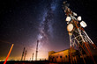 © Alberto Menendez/ADDICTIVE STOCK - From below wonderful view of media antenna and silhouettes of electricity high voltage power towers against night city on horizon and gorgeous Milky Way in clear sky