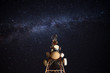 © Alberto Menendez/ADDICTIVE STOCK - From below wonderful view of media antenna and silhouettes of electricity high voltage power towers against night city on horizon and gorgeous Milky Way in clear sky