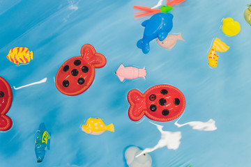 Several igushek in the form of marine fish swim in the water. The toys are very bright colors and look beautiful against the background of blue water.