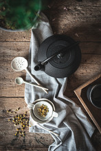 From Above Composition Of Black Teapot And White Bowl And Chamomile Herbs On Wooden Table