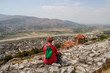 The view from the heights of the famous tourist city of Berat, Albania. Medieval city surrounded by mountains. A young girl tourist sits on the background of the church of St. Michael.