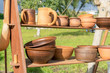 Many clay dishes on wooden shelf in Park. Pottery fair. Potter's craft. Kitchen utensils