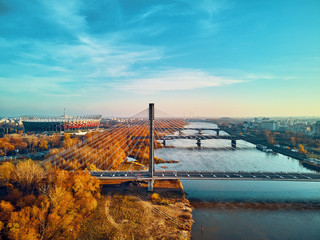 Wall Mural - Beautiful panoramic aerial dsrone view to Swietokrzyski Bridge (Polish: Świętokrzyski) and The PGE Narodowy or National Stadium - football stadium located in Warsaw, Poland in autumn evening at sunset