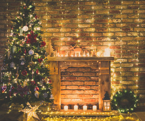 Beautiful decorated interior. Fireplace with wooden mantelpiece with fairy lights, handmade ornaments, candles and lantern, Christmas tree to the side, toned, selective focus