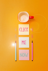 Poster - Text sign showing Click Me Now. Business photo text Internet helping desk Press the button Online Icon Nertwork Coffee cup blank colored sticky note two ballpoints clips yolk background