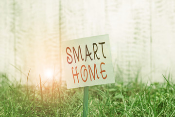 Text sign showing Smart Home. Business photo showcasing automation system control lighting climate entertainment systems Plain empty paper attached to a stick and placed in the green grassy land