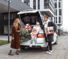 Christmas Shopping During Sale. Happy Family Standing Near Car With A Lot Of Gifts   And Fir Tree After Shopping. 