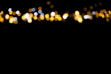 Golden glitter bokeh lights on black background, unfocused. Holiday time.