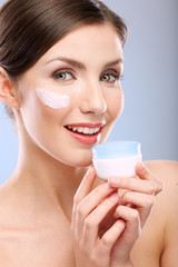 Wall Mural - Close up beauty face portrait of young woman with cream jar.