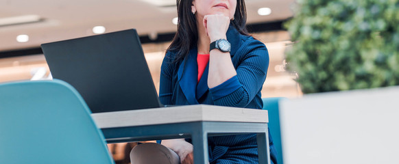 Wall Mural - Stylish business woman working on a laptop in a bright office. Woman is in a pensive pose