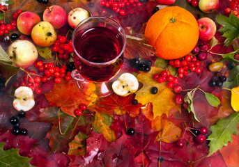Wall Mural - Mulled wine on a background of fallen autumn leaves with apples, orange and berries. Top view. Autumn background.