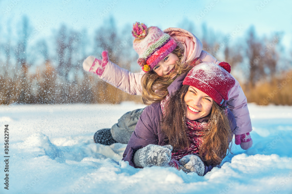 Little girl and her mother playing outdoors at sunny winter day. Active winter holydays concept. - obrazy, fototapety, plakaty 