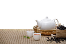 Warm Cup Of Tea With Teapot, Green Tea Leaves And Dried Herbs On The Bamboo Mat At Morning Isolate White Background With Empty Space, Organic Product From The Nature For Healthy With Traditional