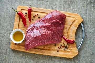 Canvas Print - Piece of raw beef with spices and oil on a wooden cutting board