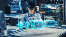 Industrial Factory Chief Engineer Wearing AR Headset Designs A Prototype Of An Electric Motor On The Holographic Projection Blueprint. Futuristic Virtual Design Of Mixed Technology Application.