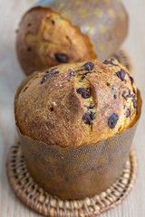 Close-up detail on top view of two panettones with chocolate chips, on wooden table in vertical