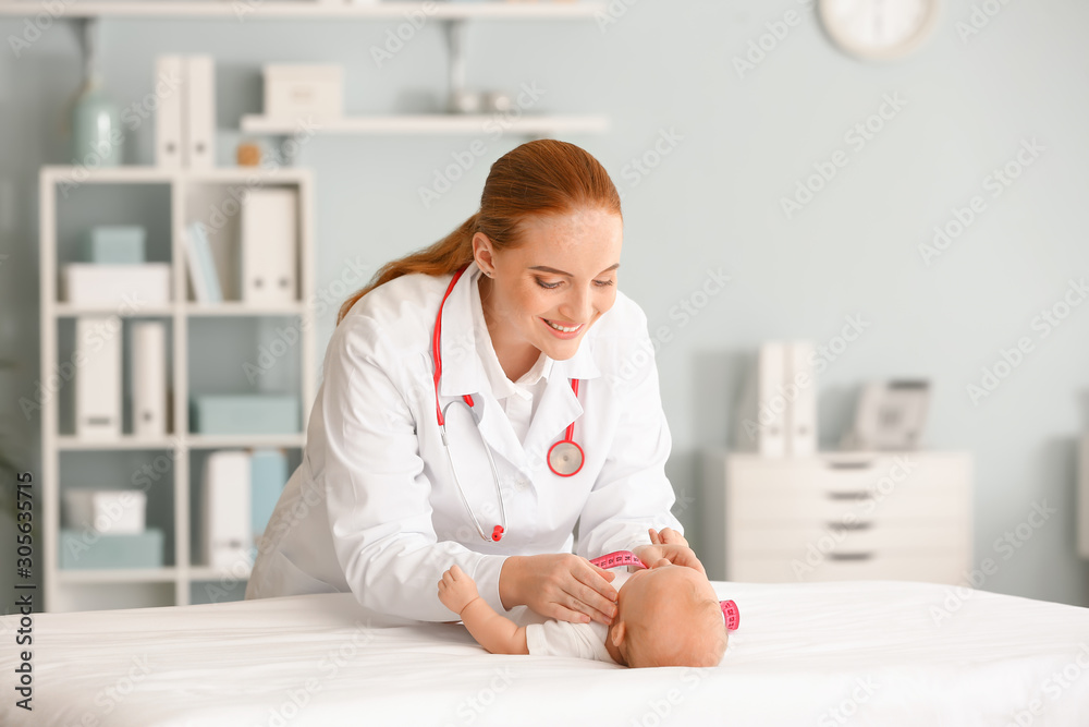 Pediatrician examining cute baby in clinic