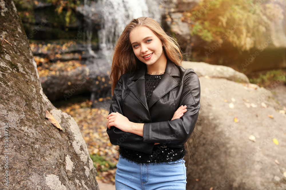 Beautiful young woman near waterfall