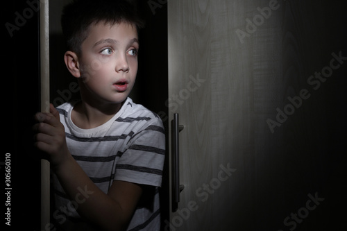 Fotografía Scared little boy hiding in wardrobe. Domestic violence concept