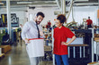 © Dusan Petkovic - Graphic engineer holding bucket with liquid glue and explaining to his new female employee how to use it. Printing shop interior. In background are printing machines.
