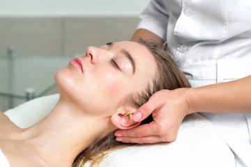 Wall Mural - Young woman receiving a head massage by female beautician in the spa beauty salon close up.