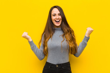 young pretty woman looking extremely happy and surprised, celebrating success, shouting and jumping job or business concept