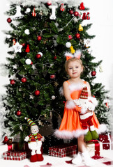 Christmas, little girl in a fluffy rim by the Christmas tree, smile and laugh.