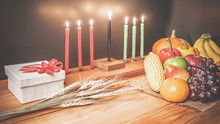 Kwanzaa Holiday Concept With Decorate Seven Candles Red, Black And Green, Gift Box, Pumpkin,corn And Fruit On Wooden Desk And Background.