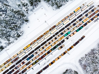 Aerial view of colorful freight train cars on the railway station. Wagons with goods on railroad. Industrial conceptual scene with trains.