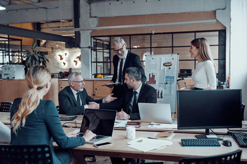 Wall Mural - Modern marketing professionals in elegant formalwear discussing fresh business ideas while working in the office