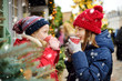 © MNStudio - Two adorable sisters drinking hot chocolate on traditional Christmas fair in Riga, Latvia. Children enjoying sweets, candies and gingerbread on Xmas market.
