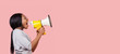 Young woman shouting in megaphone over pink background