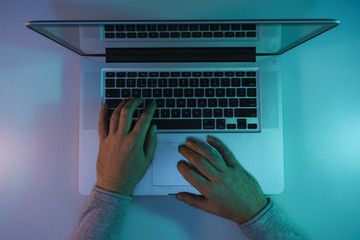 Aufkleber - Man working night online silver laptop in the color light on a table night background. Top view.