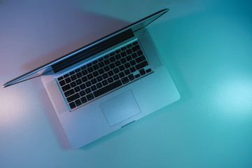 Aufkleber - Beautiful silver laptop in the color light on a table and night background. Top view.