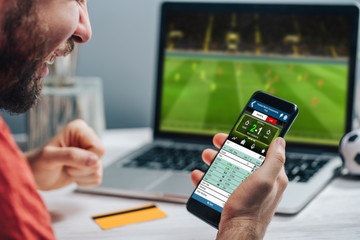 Guy being happy winning a bet in online sport gambling application on his mobile phone