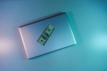 Aufkleber - Beautiful silver laptop and cash dollars banknote in the color light on a table and  background. Work night concept. Top view.