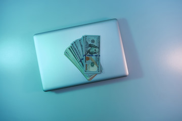 Aufkleber - Beautiful silver laptop and cash dollars banknote in the color light on a table and  background. Work night concept. Top view.