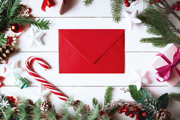 Christmas composition. Christmas gift, , pine cones, fir branches on wooden white background. Empty christmas card with envelope  Flat lay, top view, copy space. New Year.