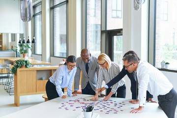 Wall Mural - Smiling businesspeople trying to solving a jigsaw puzzle togethe