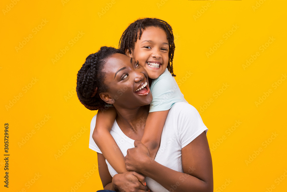 Black daughter embracing her happy cheerful mother - obrazy, fototapety, plakaty 