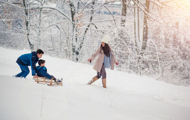 Wall Mural - Young, beautiful mom and her cute little boy enyoing winter, sledding