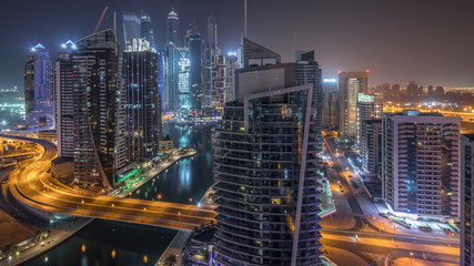 Aerial view of Dubai Marina residential and office skyscrapers with waterfront night timelapse