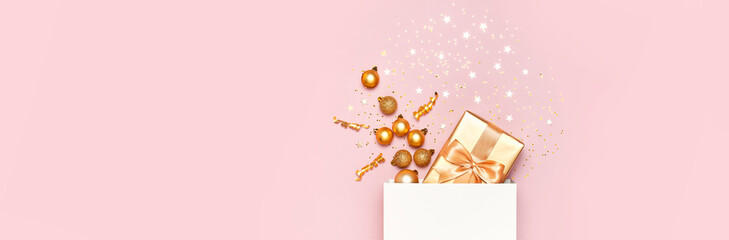 Wall Mural - Beautiful golden gift white paper bag confetti stars Christmas balls on pink background top view Flat lay. New Year presents Festive decorations 2020 celebration. Merry Christmas Happy Holidays card