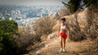Teen in red shorts and white sneakers running on trail on mountain