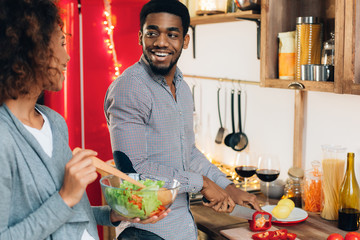 Vegetarian african-american couple cooking salad in kitchen