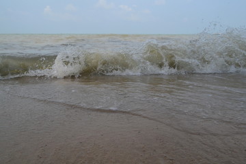 Brown-ish sea waves beside seashore, sand captured in daytime.