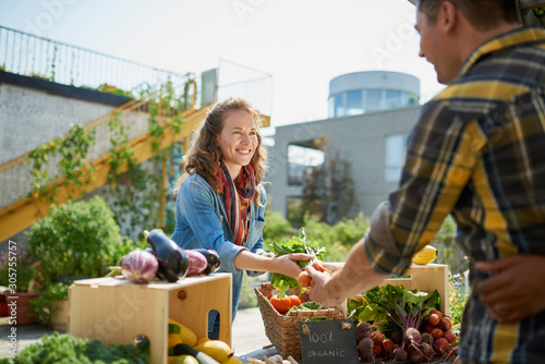 Fotomural Friendly woman tending an organic vegetable stall at a farmer's