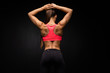 Rear view of a fit strong young woman with a muscular toned body wearing sportswear looking to the side, on grey background