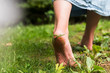 © Jamie Grill Photography/Tetra Images - Woman walking barefoot on grass